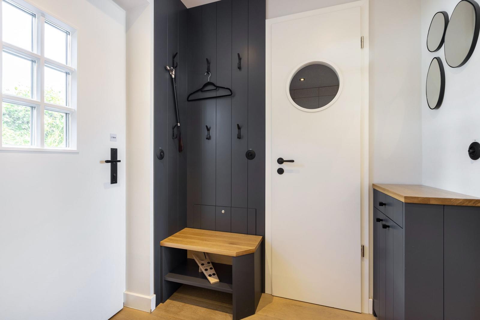 Entrance area with coat rack, bench, and mirrors on the wall.