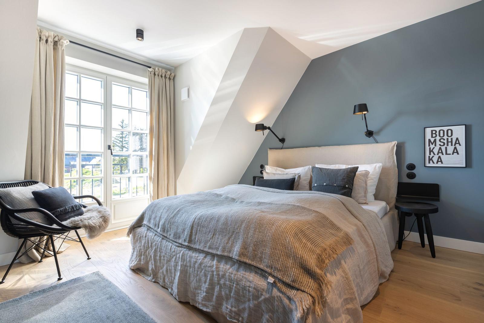 Bedroom with sloped ceiling, bed, window, and chair.