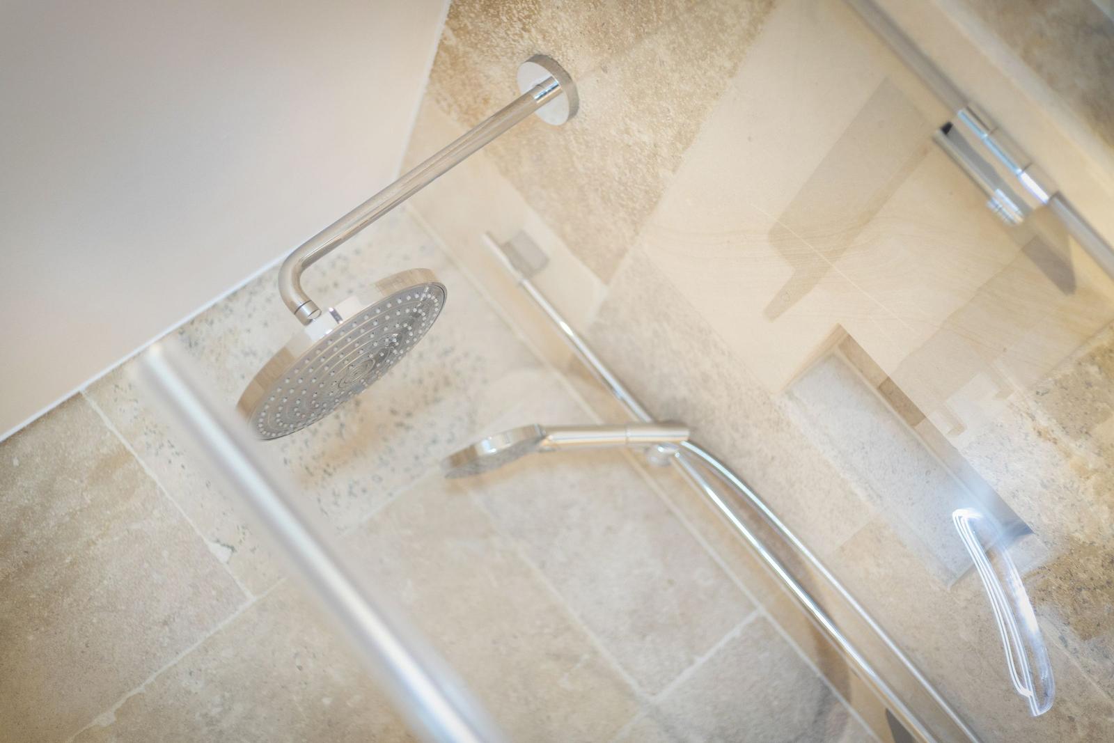 Shower area with handheld shower and showerhead mounted on wall and floor