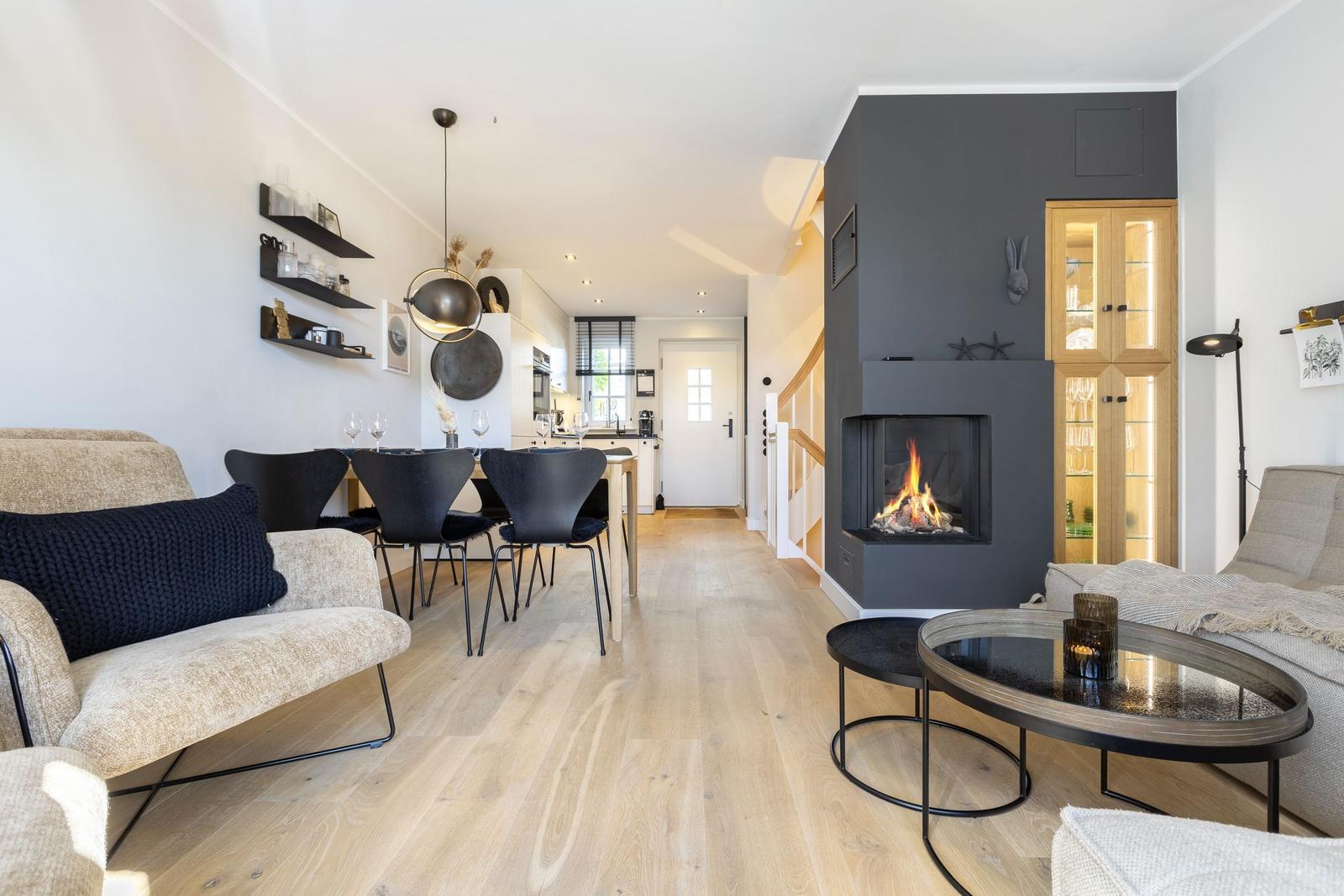 Living and dining area with fireplace, dining table, and sofa on wooden floor.
