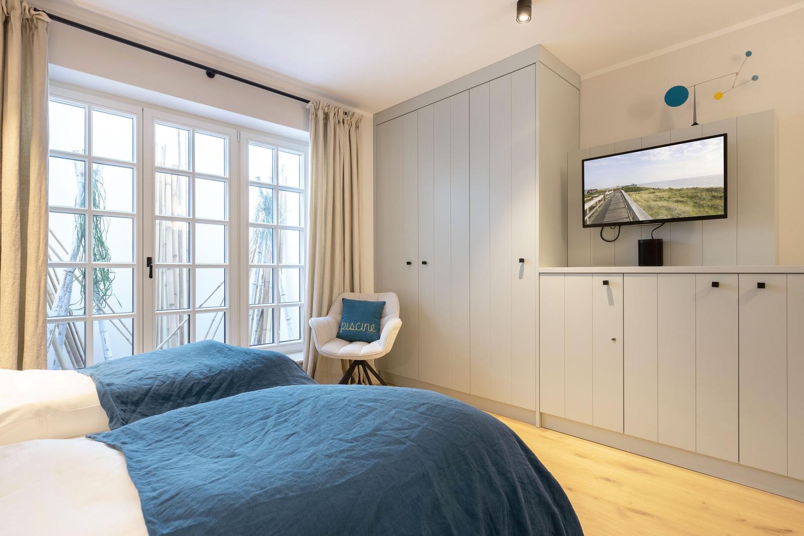 Bedroom with double bed, TV, and large window.