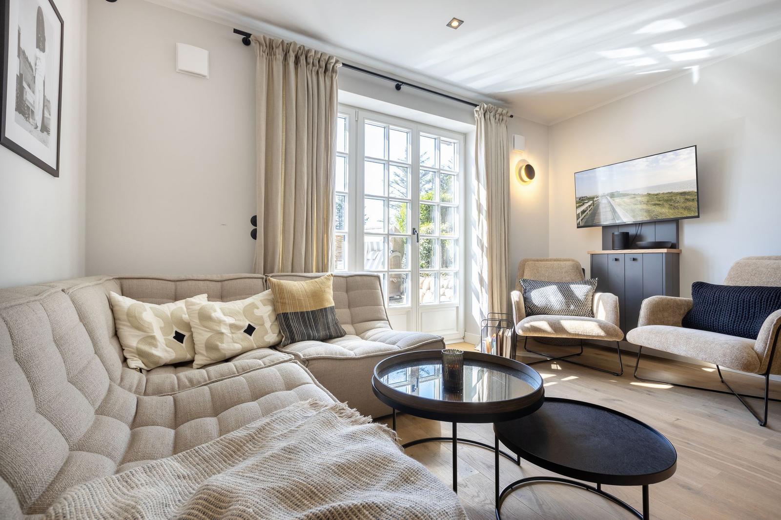 Living room with sofa, armchairs, and TV mounted on the wall