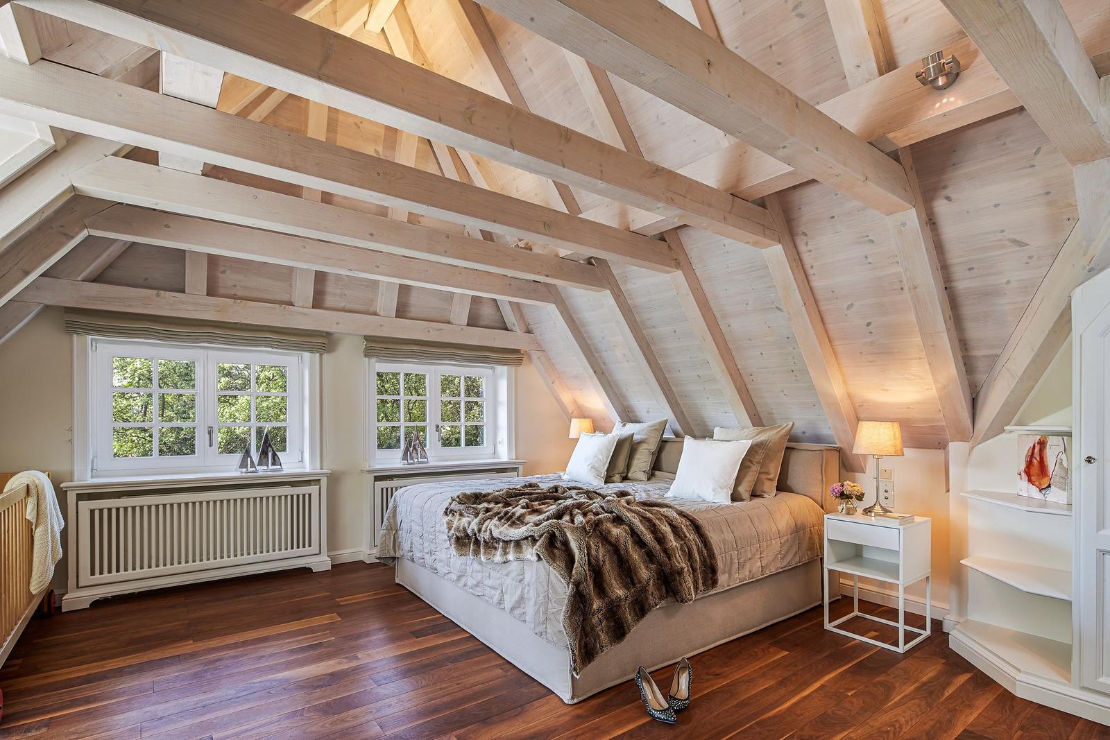 Bedroom with hardwood floor, sloped ceiling, and two windows.