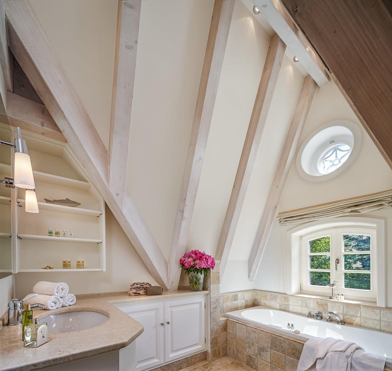 Bathroom with bathtub, sink, and wooden beams on the ceiling.