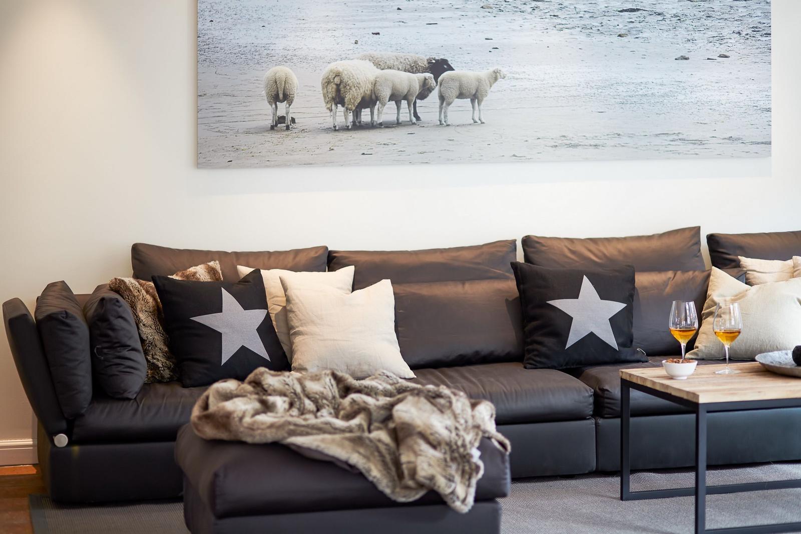 Gray sofa with pillows and blanket under wall art with sheep.