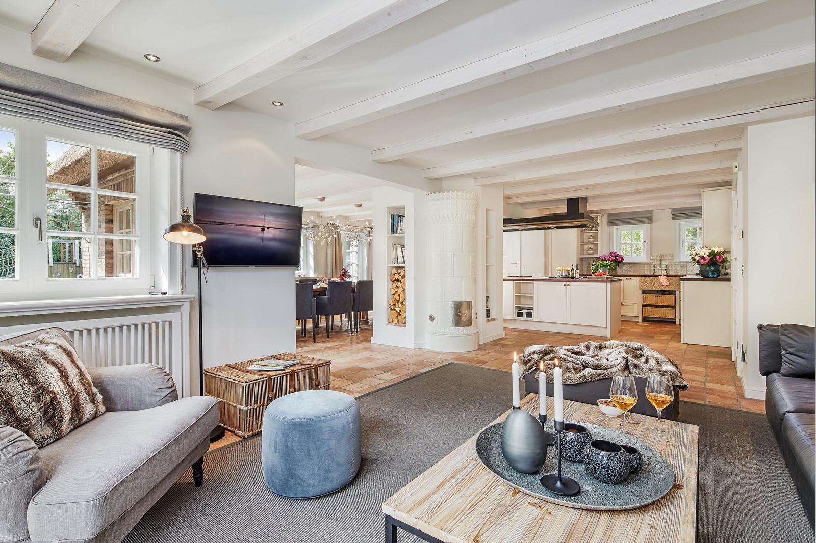 Living and dining area with kitchen. Visible beams, fireplace, and TV.