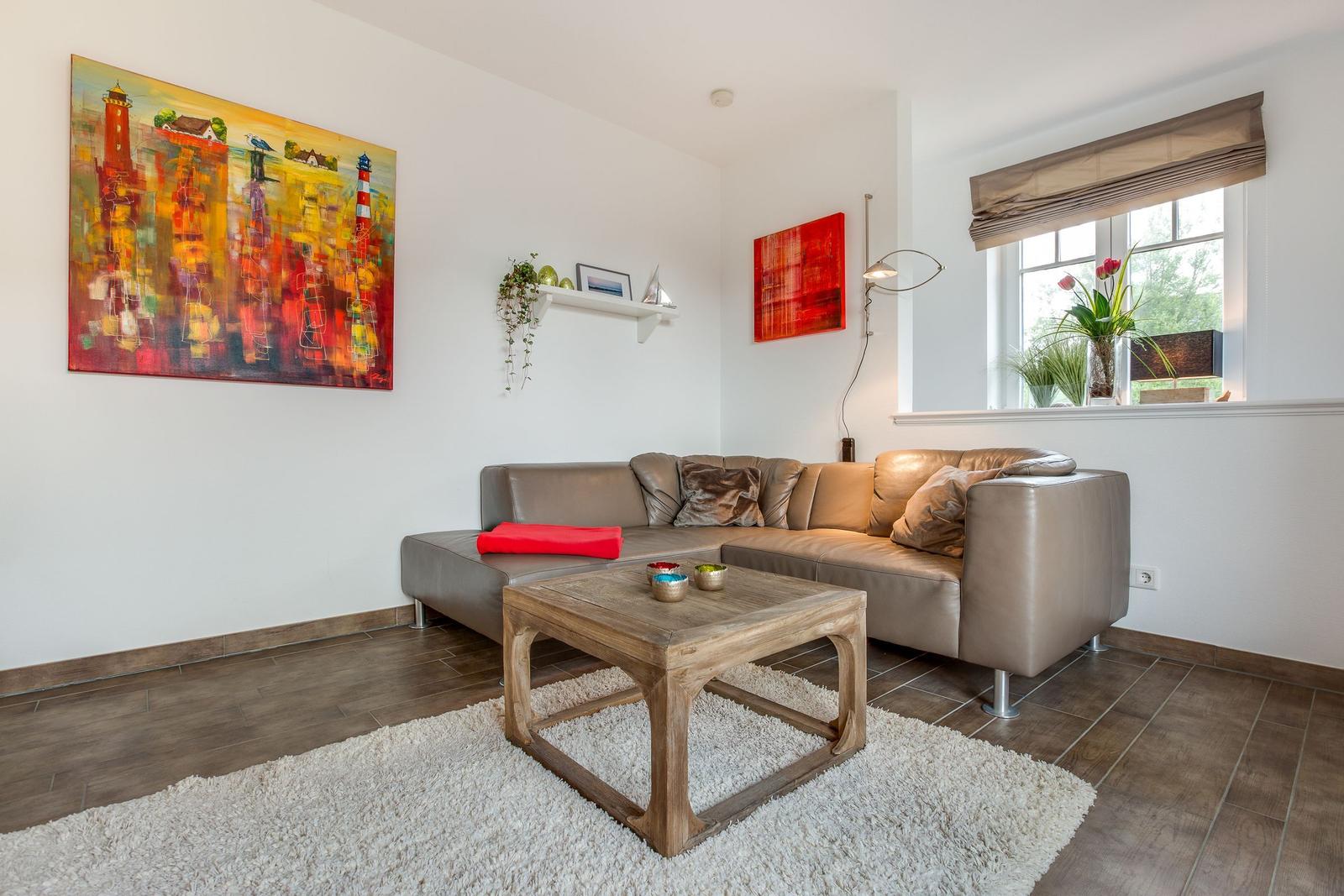 Wohnzimmer mit Ledersofa, Holztisch und Wandbildern.