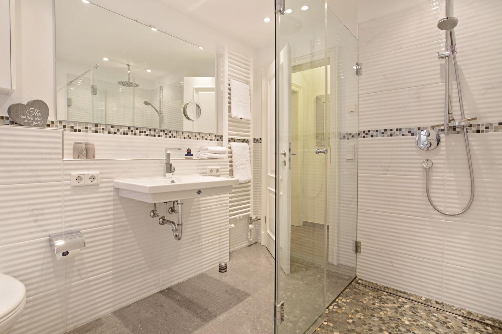 Badezimmer mit Dusche, Waschbecken und Spiegel.
