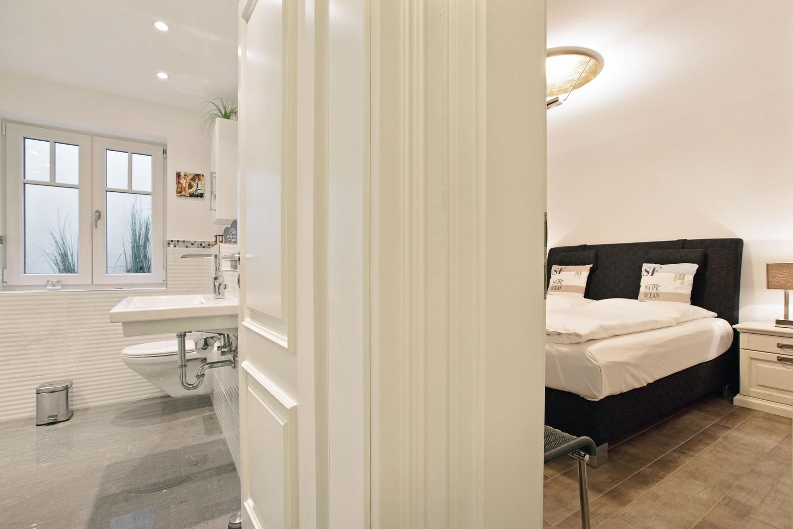 Schlafzimmer mit Doppelbett und angrenzender Badewanne