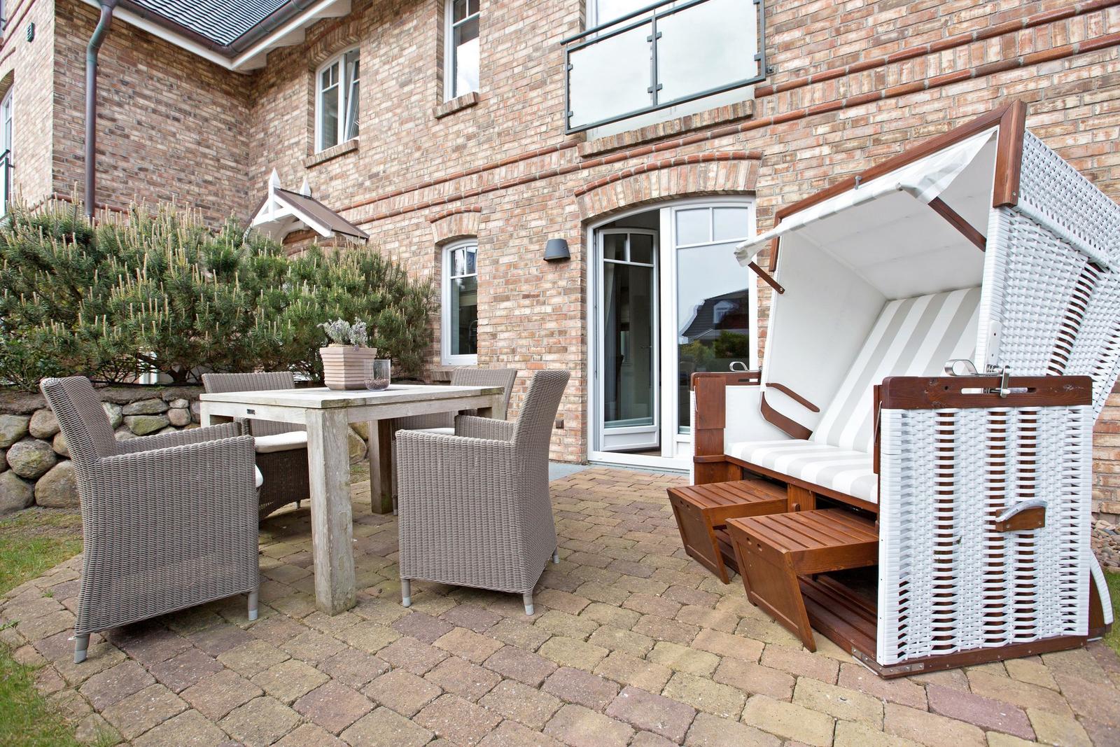 Terrasse mit Esstisch, Stühlen und Strandkorb vor Backsteinhaus