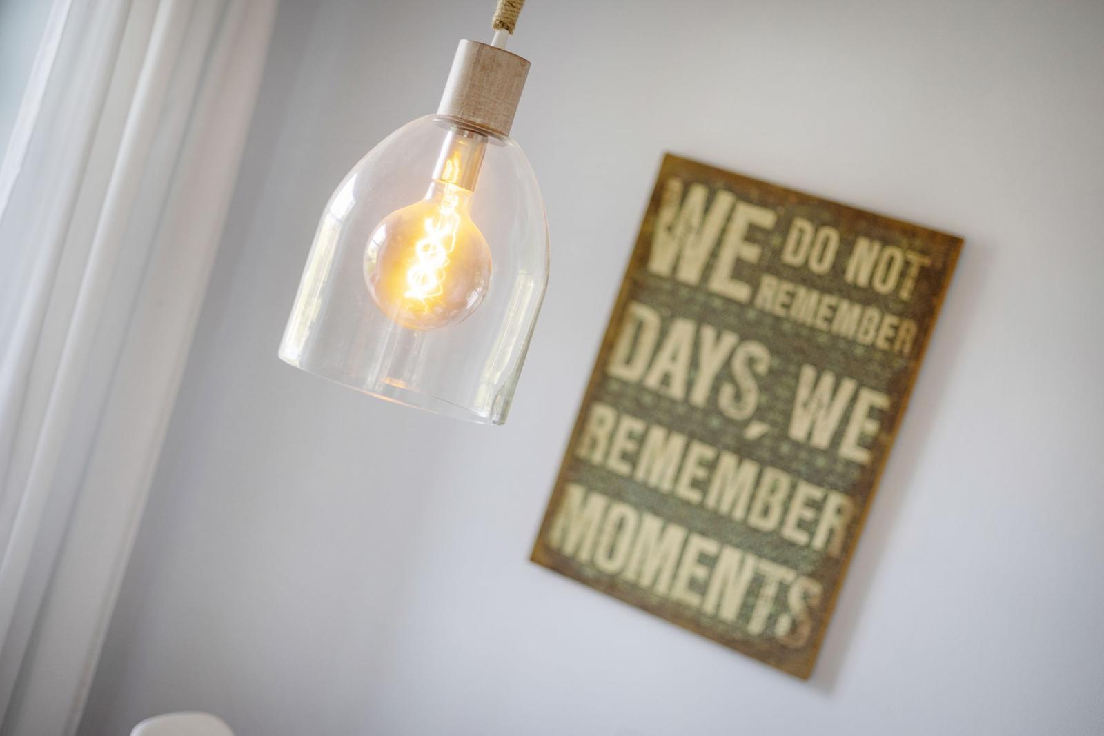 Hanging lamp with glass shade and wall plaque with text.