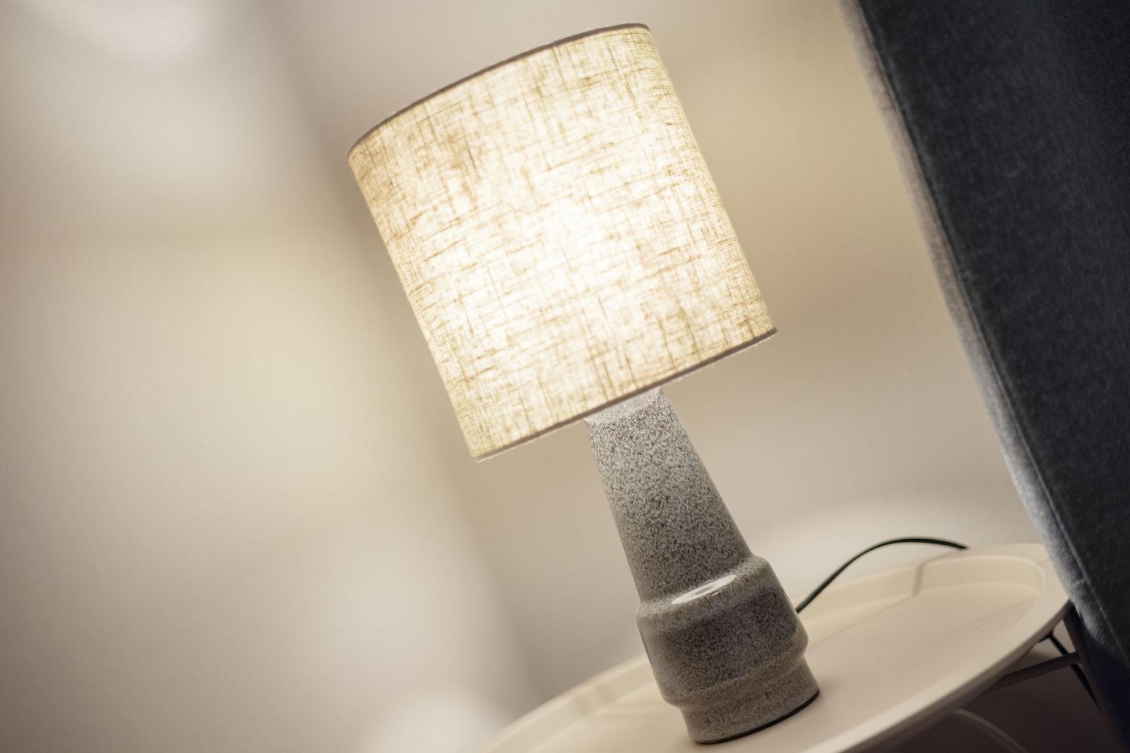 Table lamp with fabric shade on round table beside seating furniture.