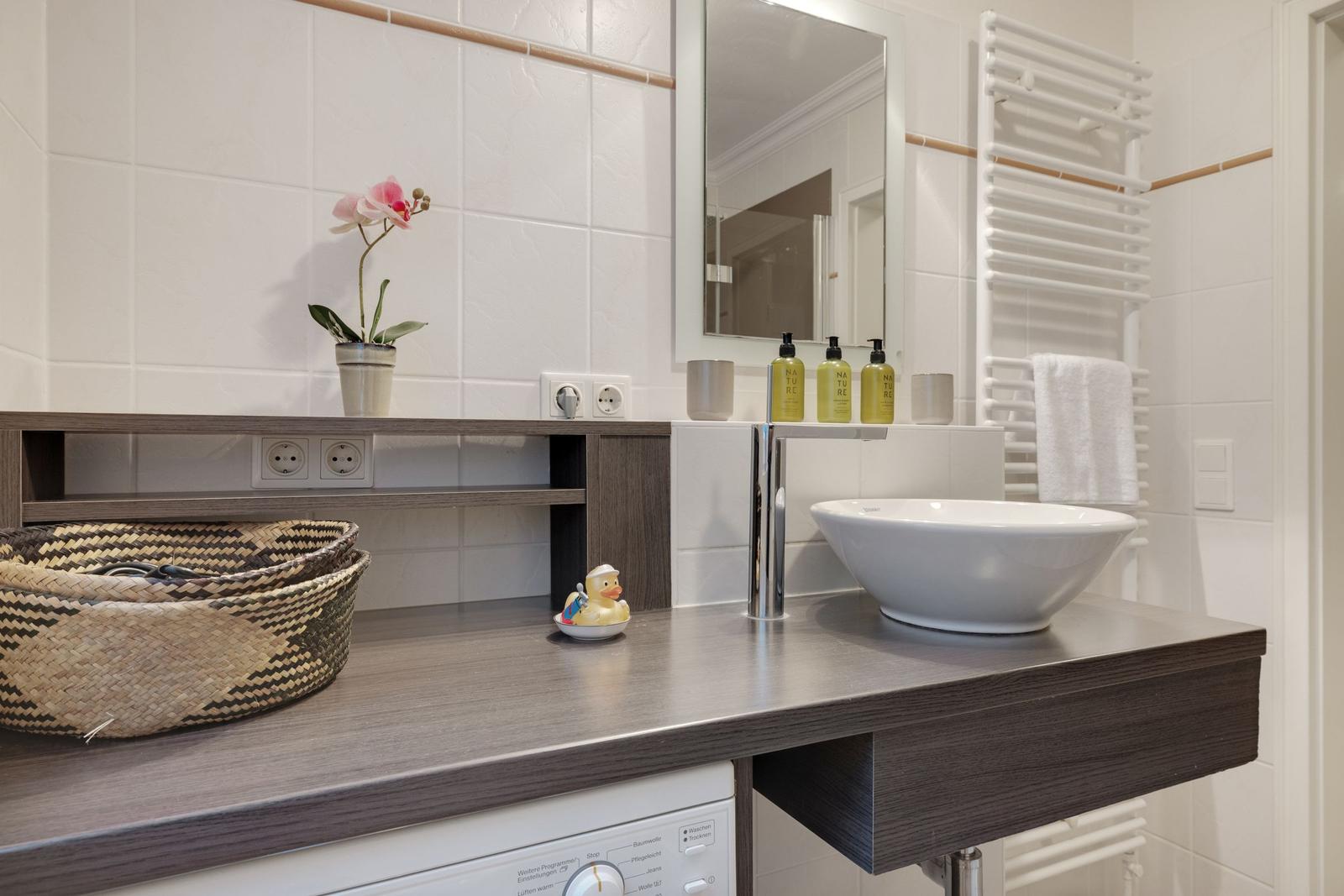 Sink with mirror, towel warmer, and decorative items.