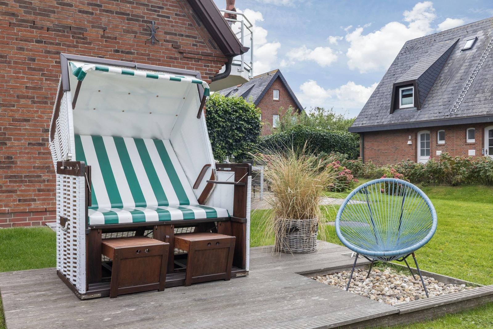 Green and white beach chair on terrace with blue rattan chair.
