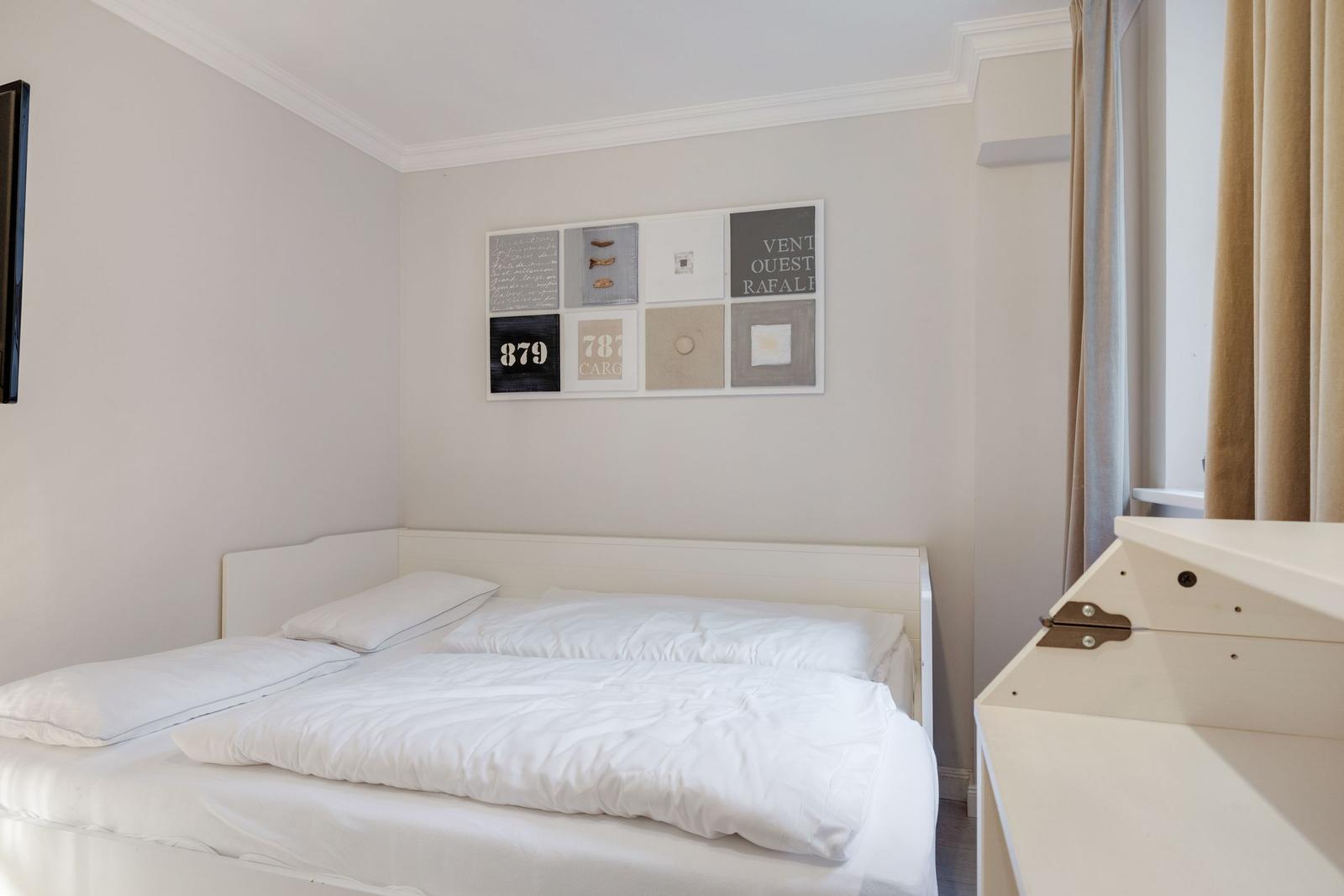 Bedroom with white bed and wall art.