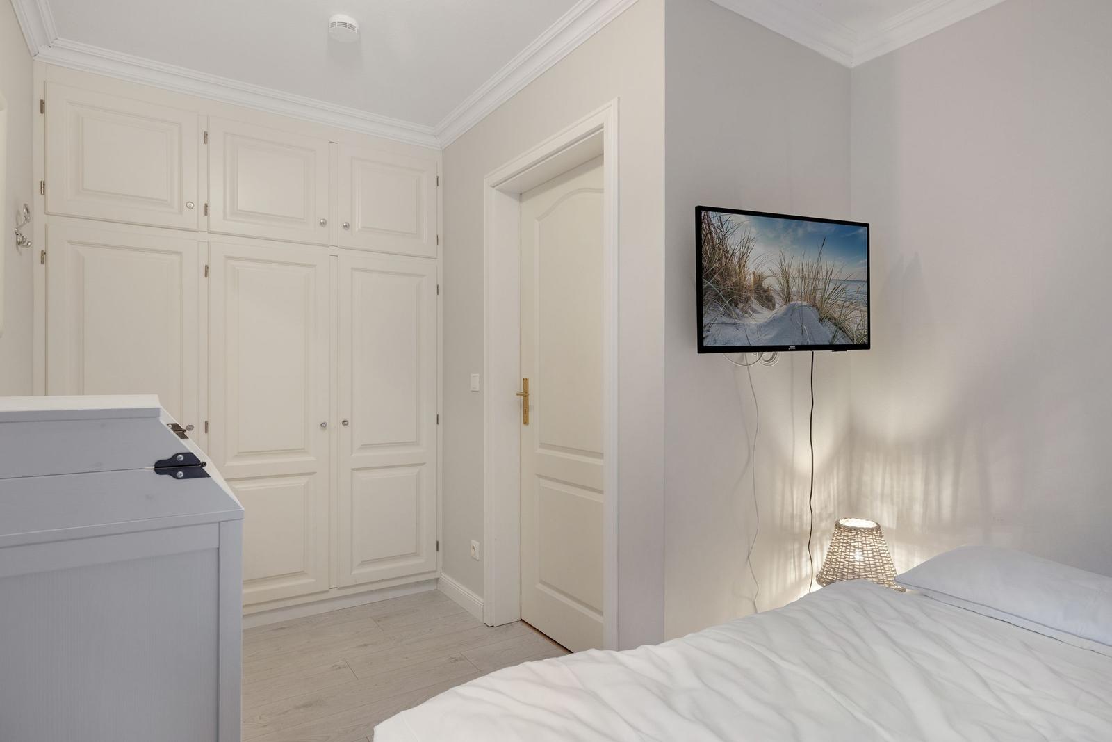 Bedroom with bed, wardrobe, and wall-mounted TV
