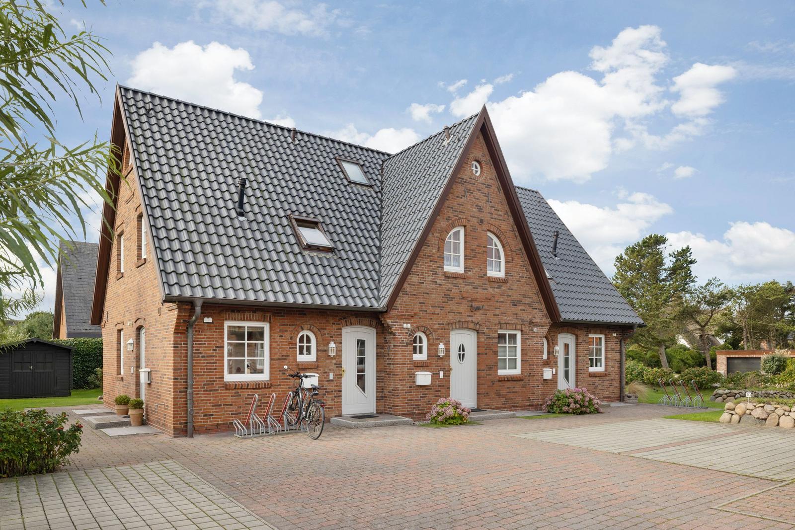 Red brick house with gray roof and multiple entrances.