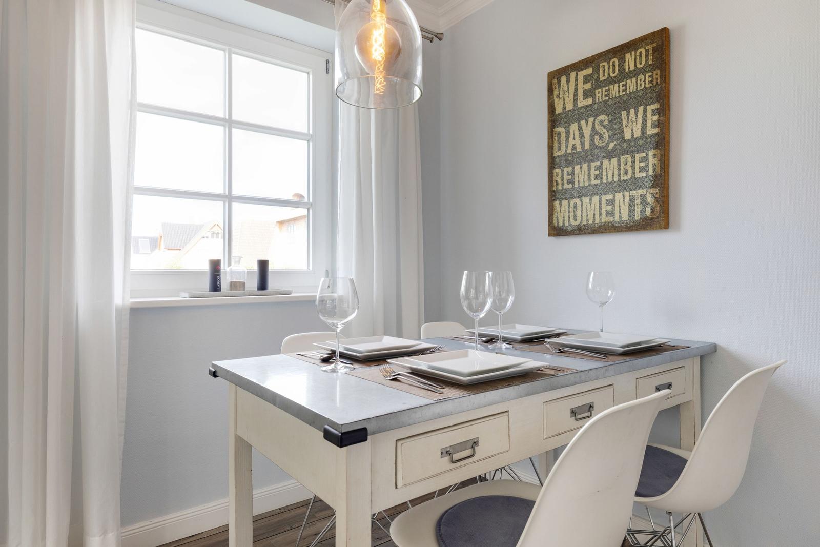 Dining area with table, chairs, and window. Wall art and pendant lamp.