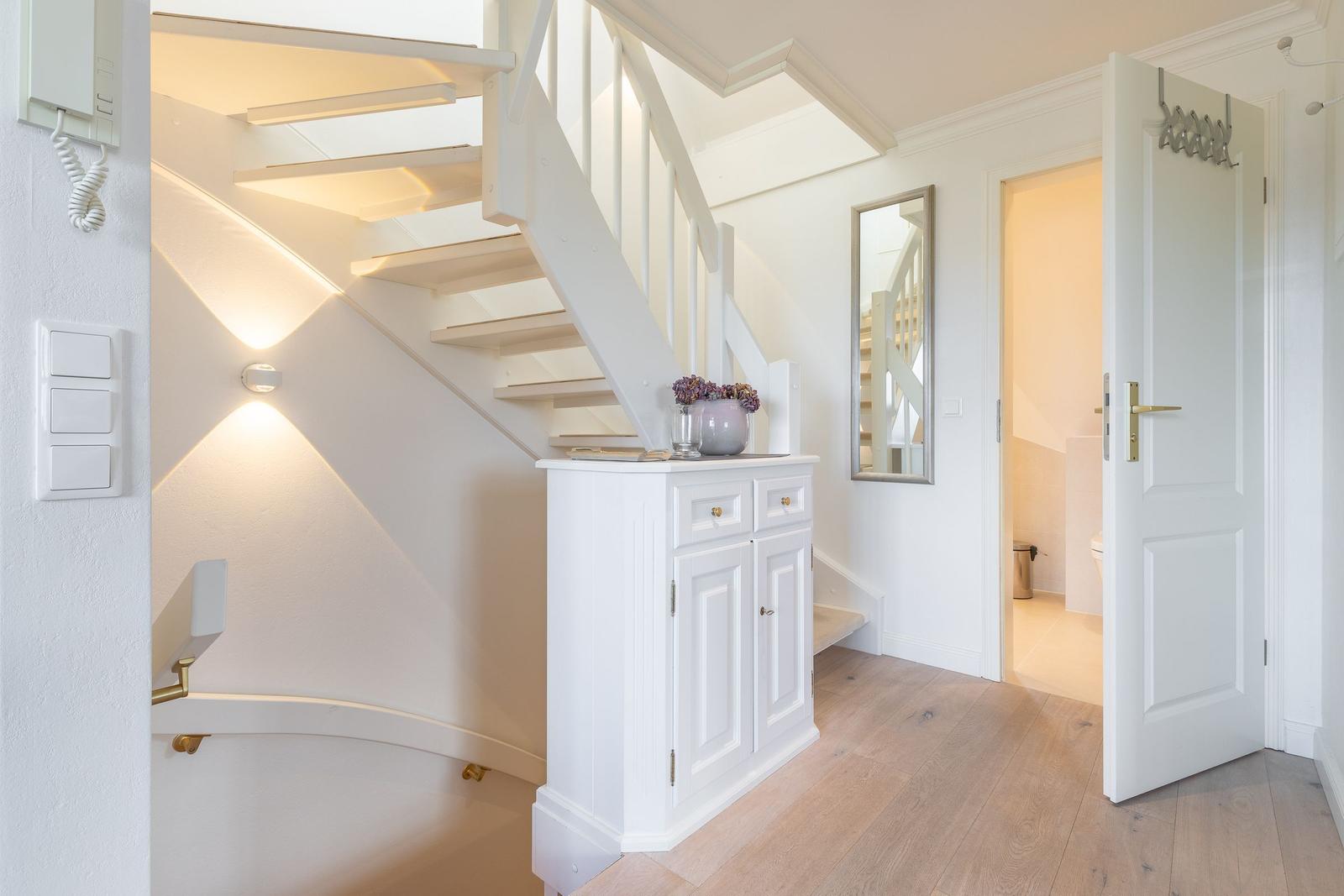 Hallway with stairs, cabinet, and door to the bathroom.