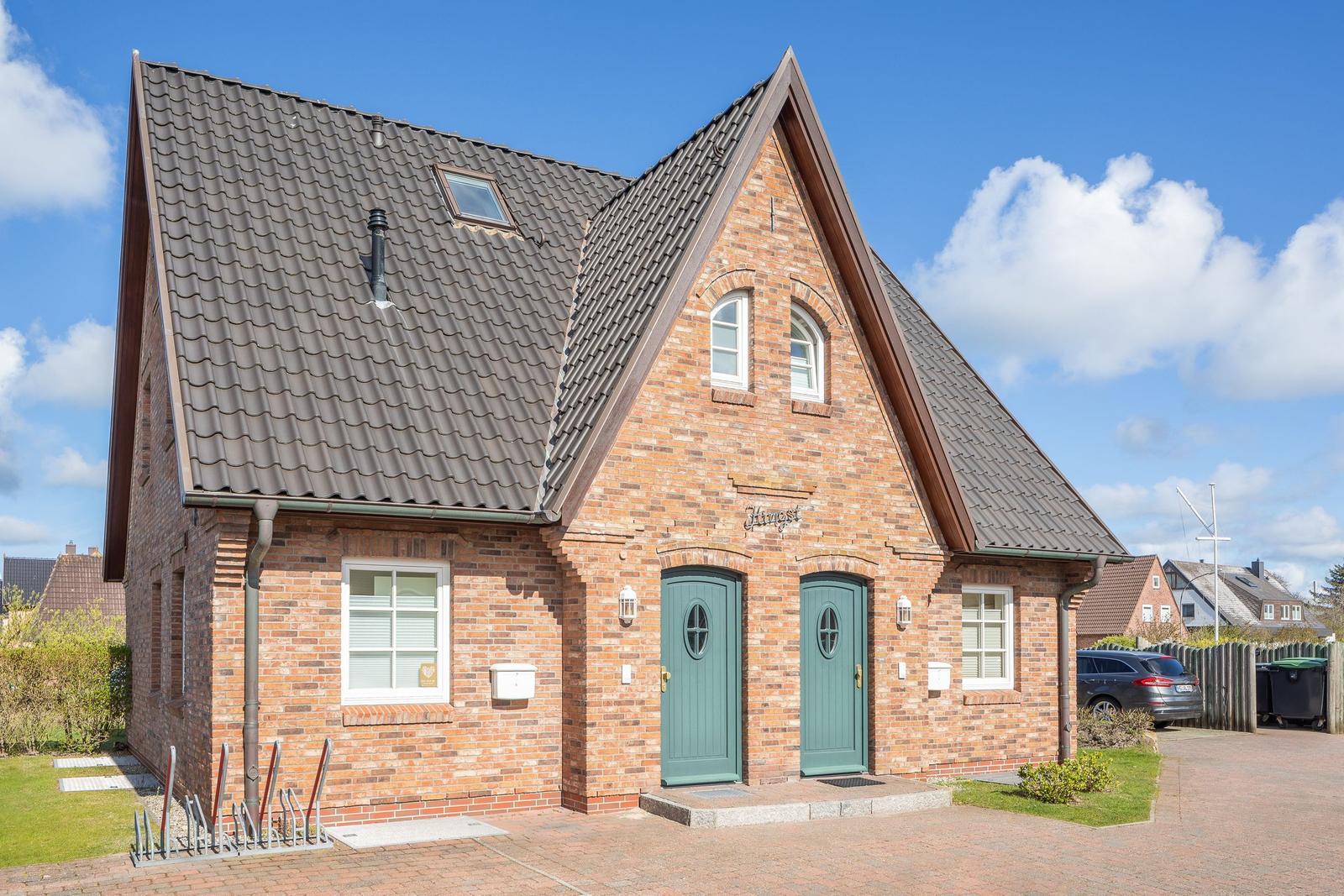 Two-story brick house with two green doors and dormer windows.