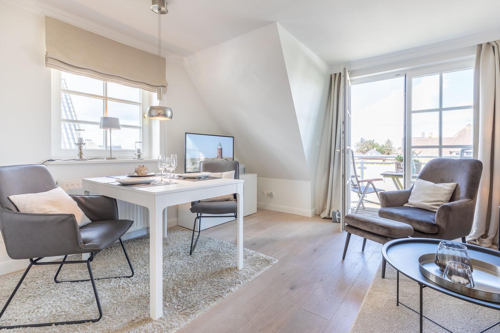Living room with dining table, armchairs, and balcony access.