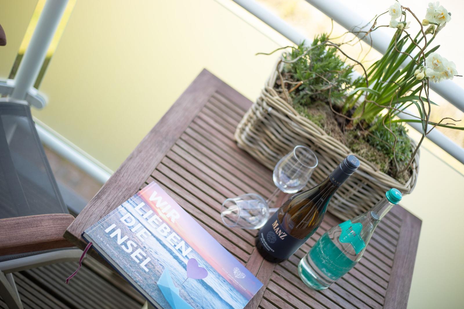 Table with wine, water, and flowers on balcony.