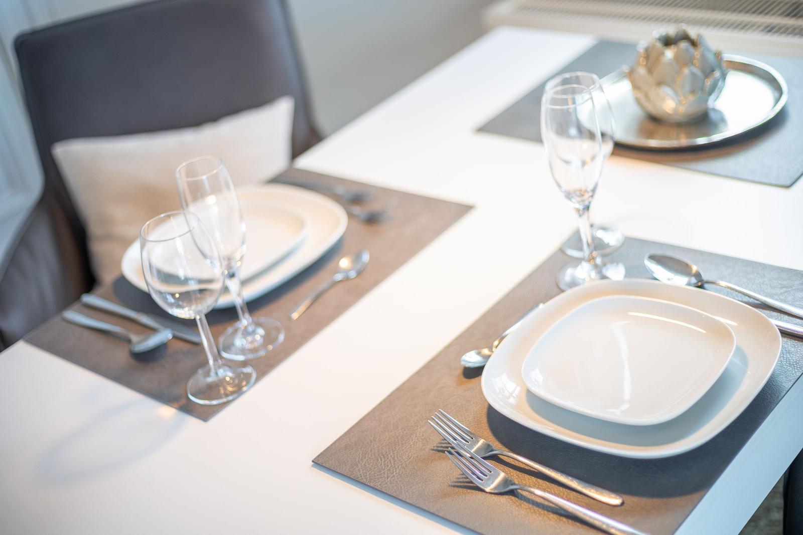 Table set for two, with plates, glasses, and cutlery.