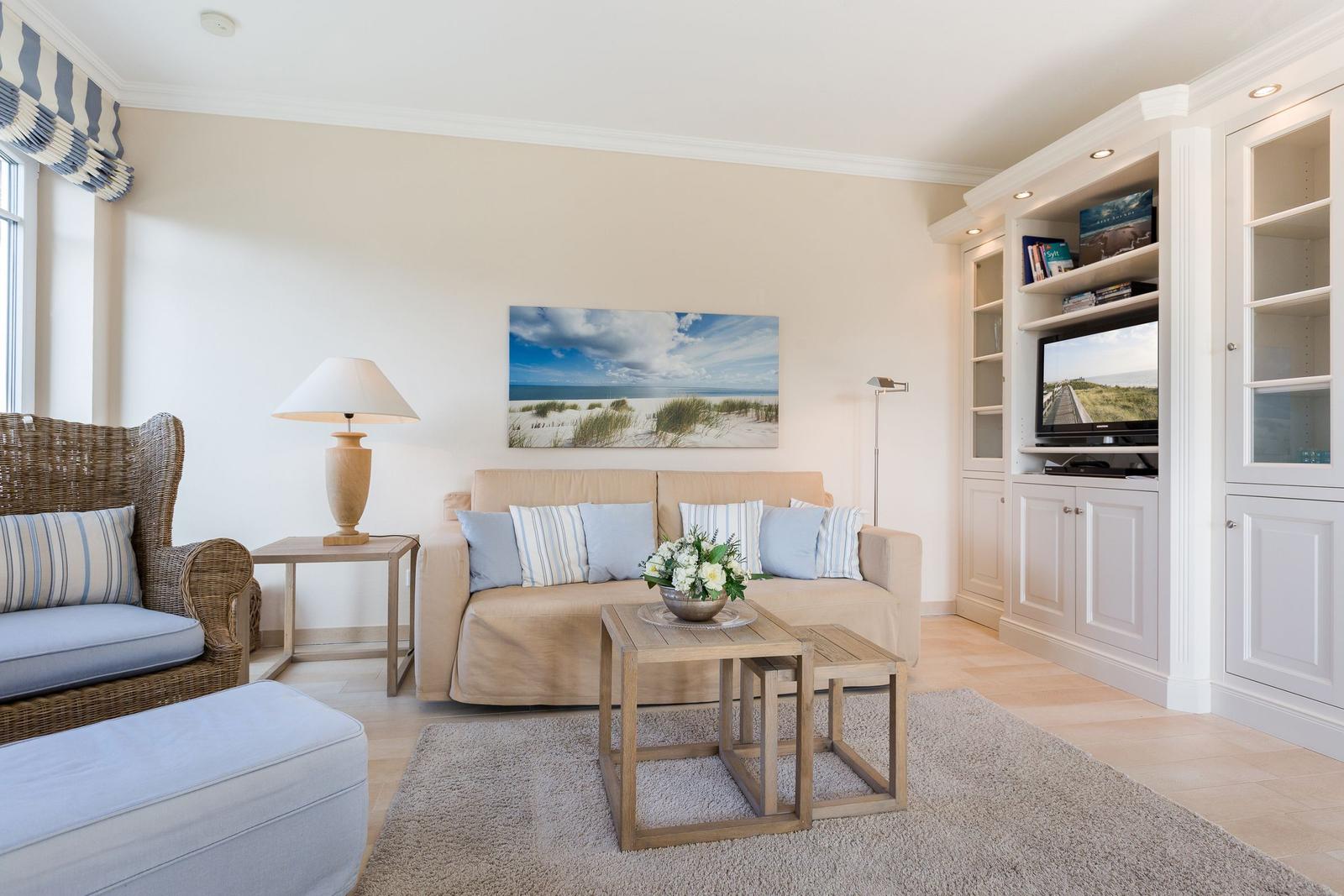 Wohnzimmer mit Sofa, Sessel, Fernseher und Wandbild.