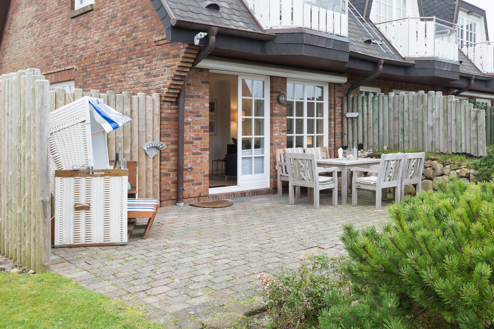 Backyard with patio, table, chairs, and beach cabana. Wooden fence and brick house.