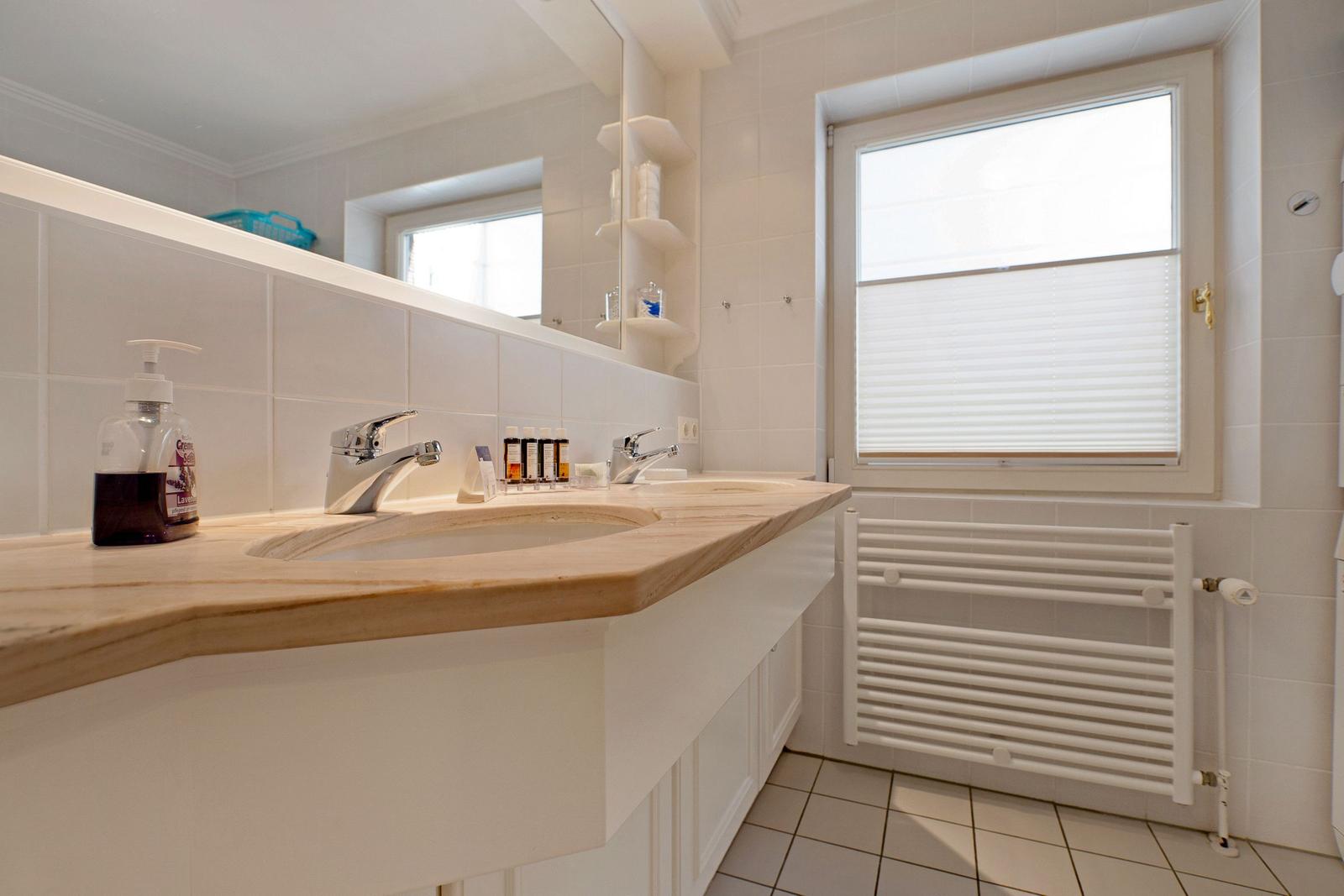 Bathroom with sink, mirror, and window with blinds.