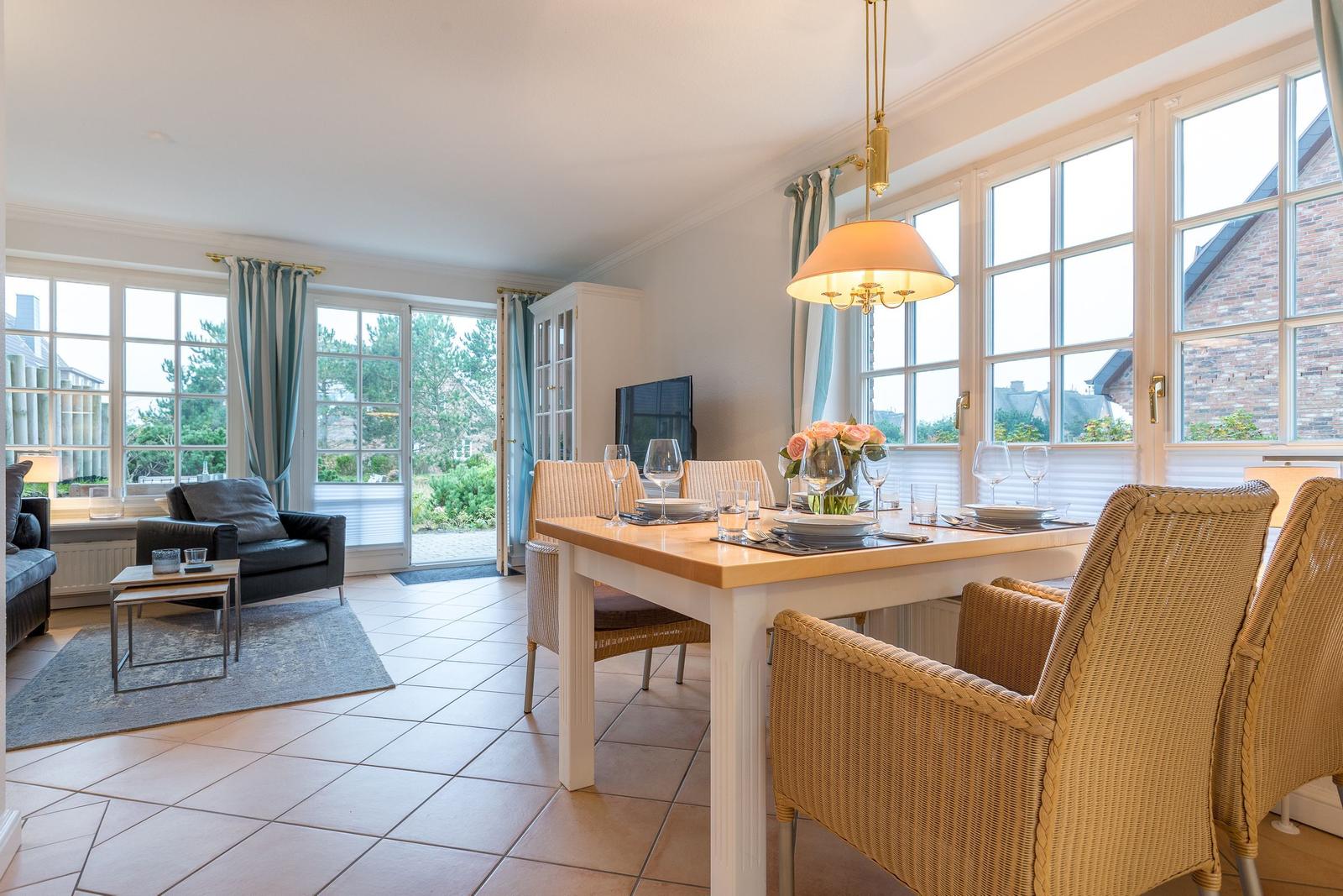Dining room with table and chairs, living area with sofa and window front.