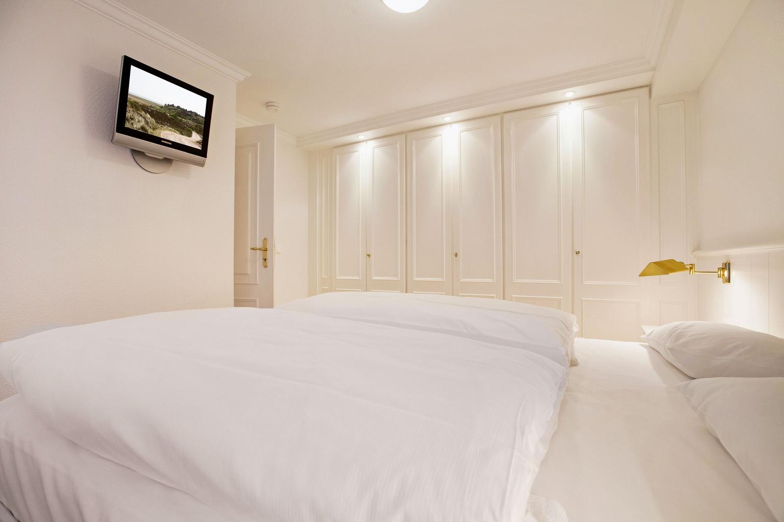 Bedroom with double bed, white wardrobes, and wall-mounted TV.