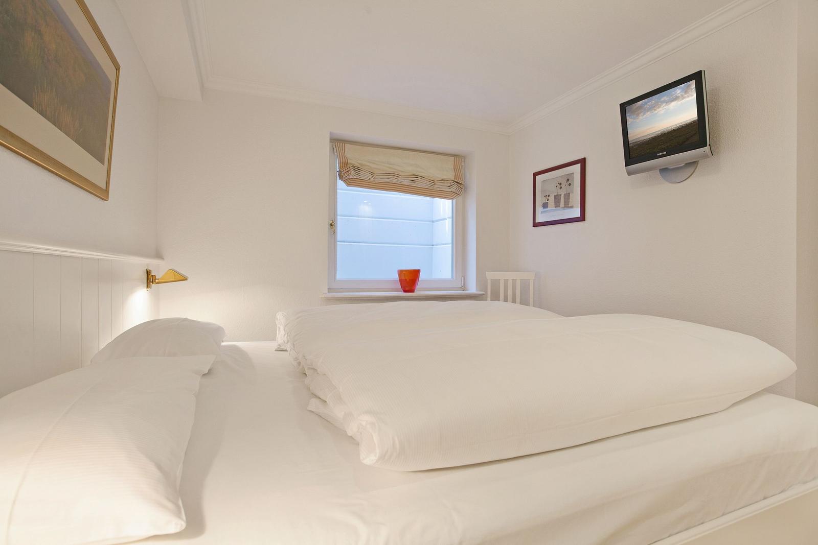 Bedroom with bed, window, and wall-mounted TV.