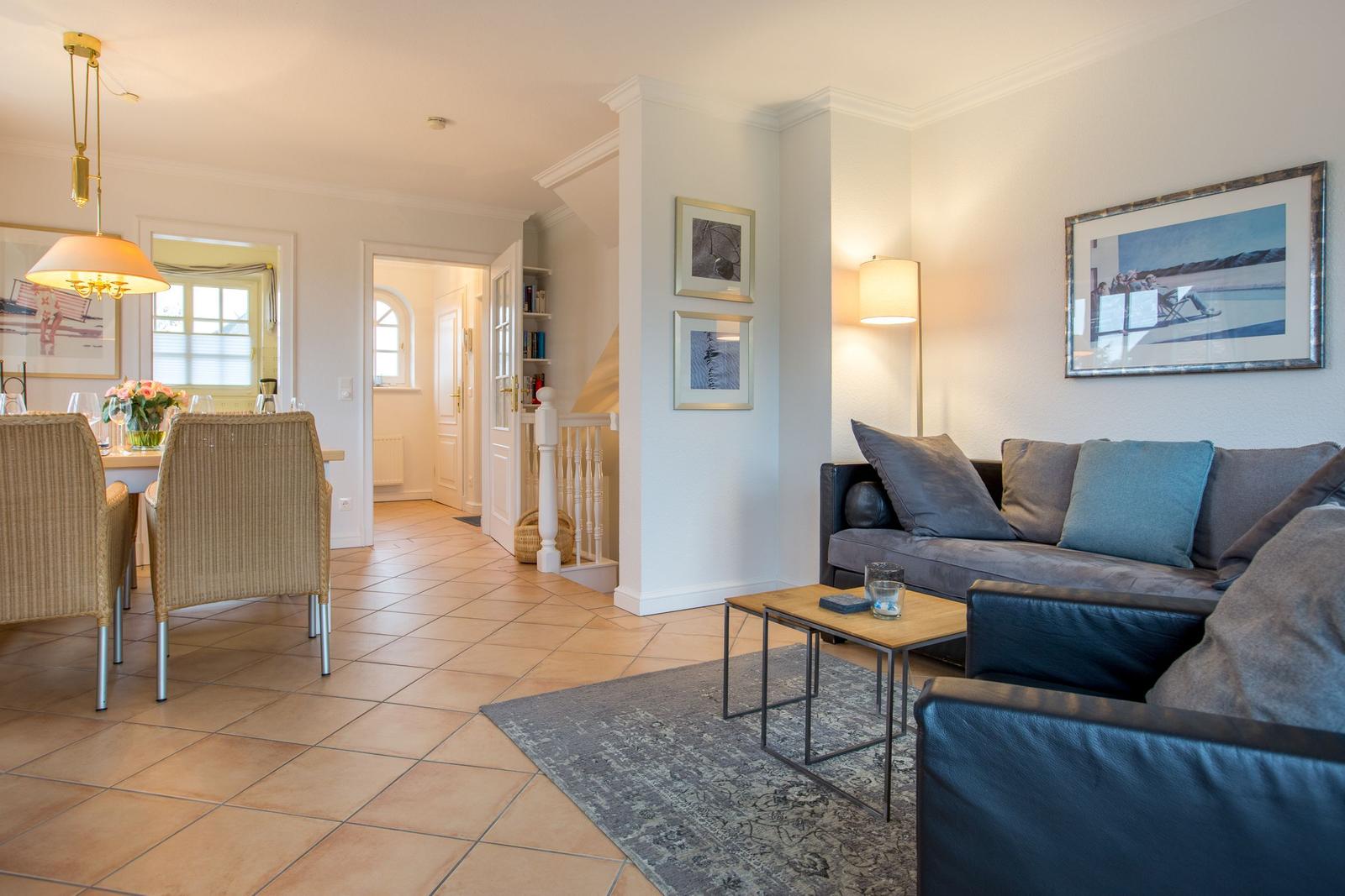 Living and dining area with sofa, table and chairs on tile floor.