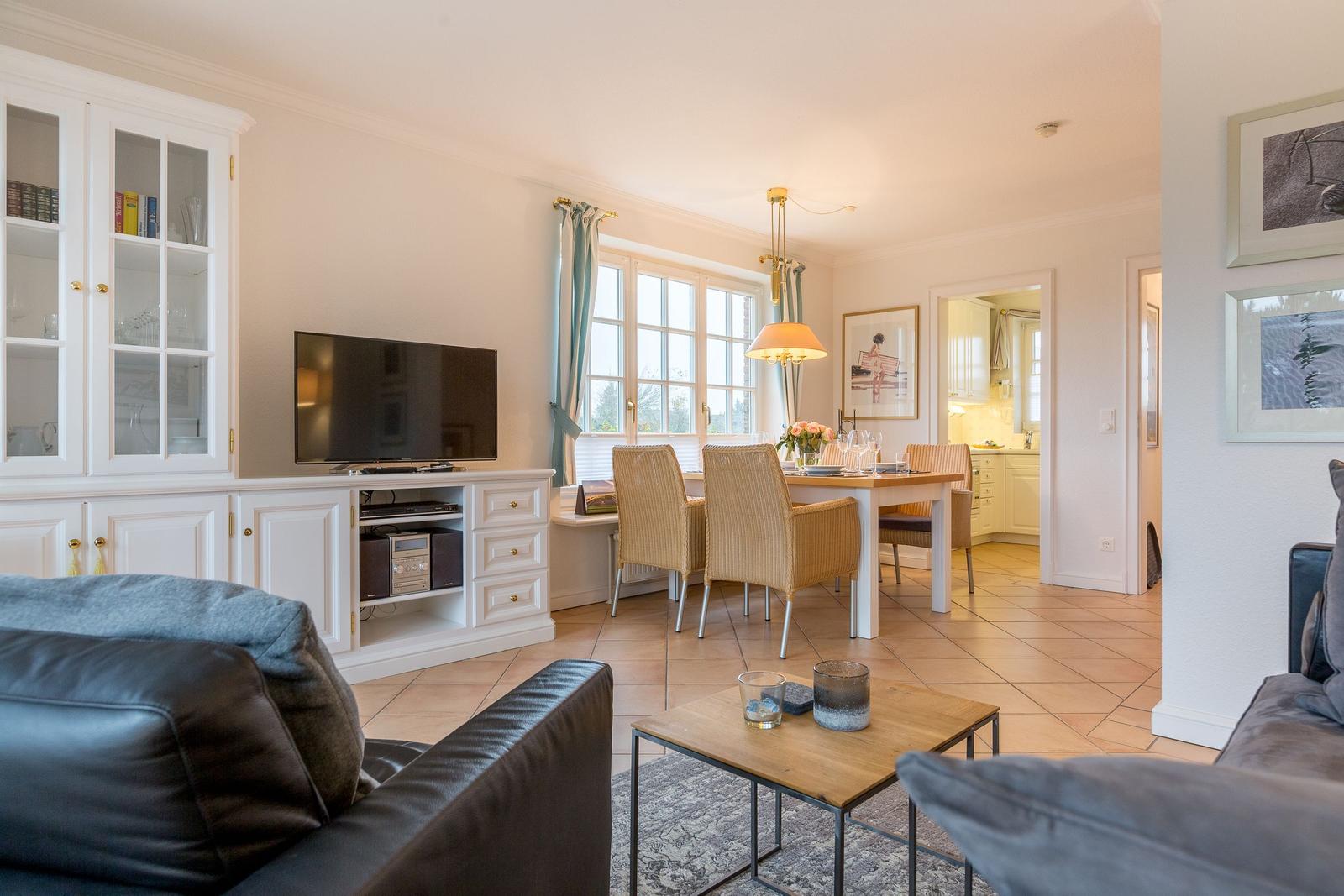 Living and dining area with TV, dining table, and windows.