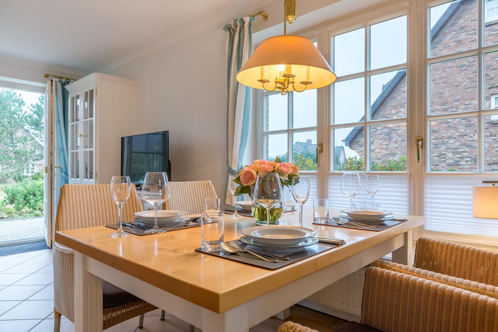 Dining room with table, chairs, and window view of house and garden.