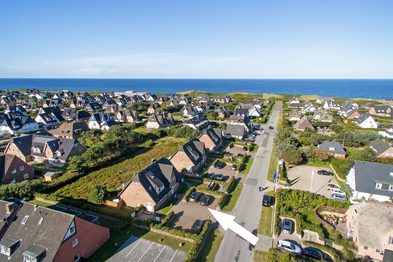 Aerial view of coastal village with houses and ocean in background.