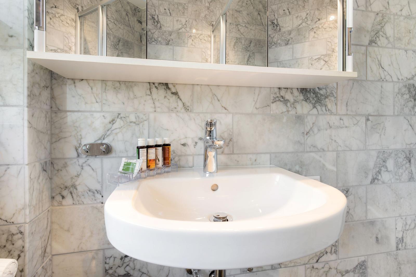 Sink with mirror and soap bottles on marble wall