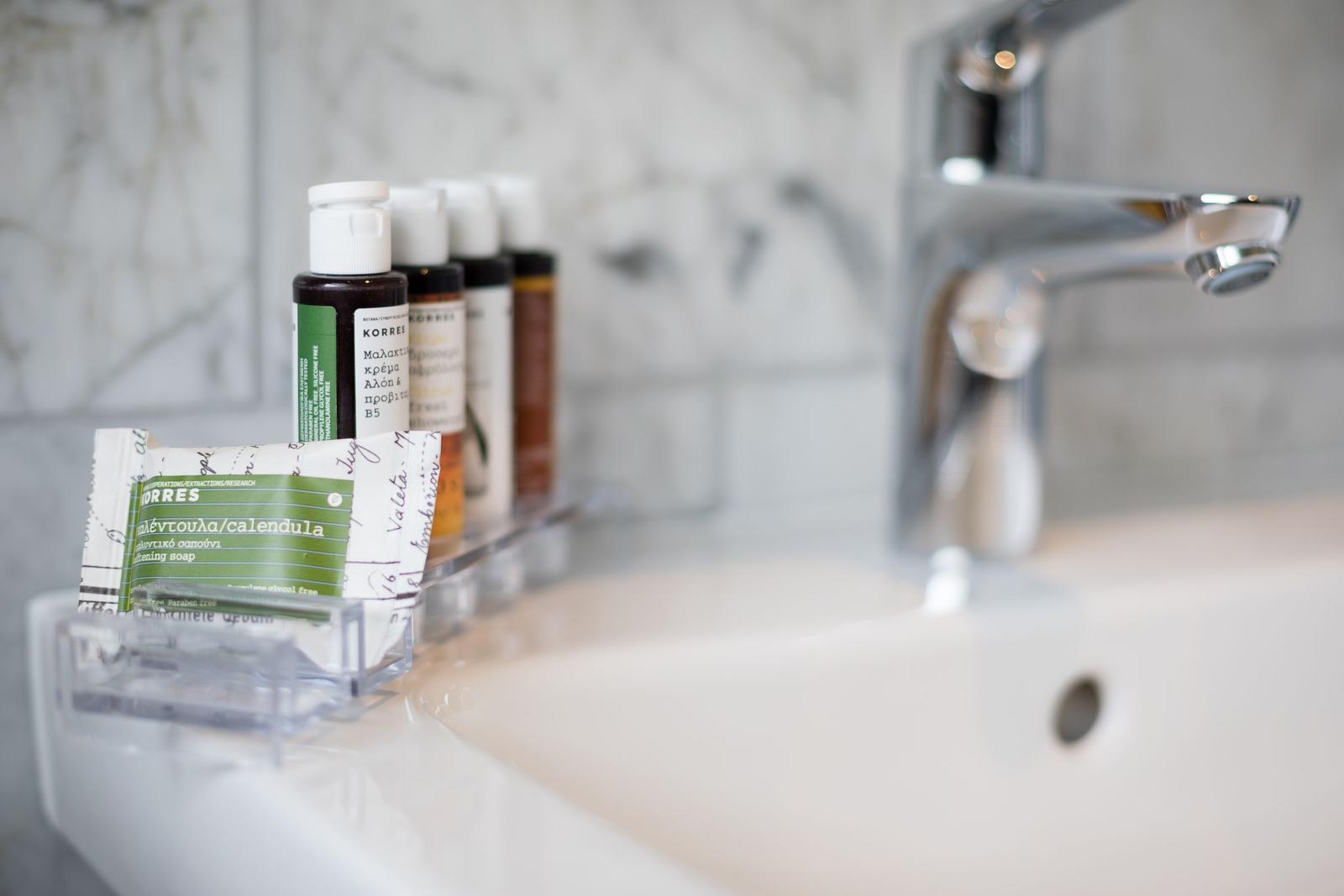 Sink with faucet and small bottles for toiletries.