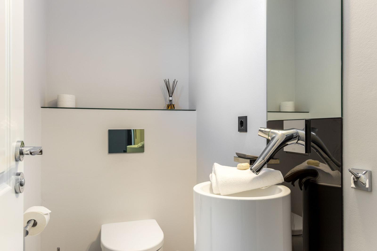 Badezimmer mit Waschbecken, Spiegel, Toilette und Handtuch