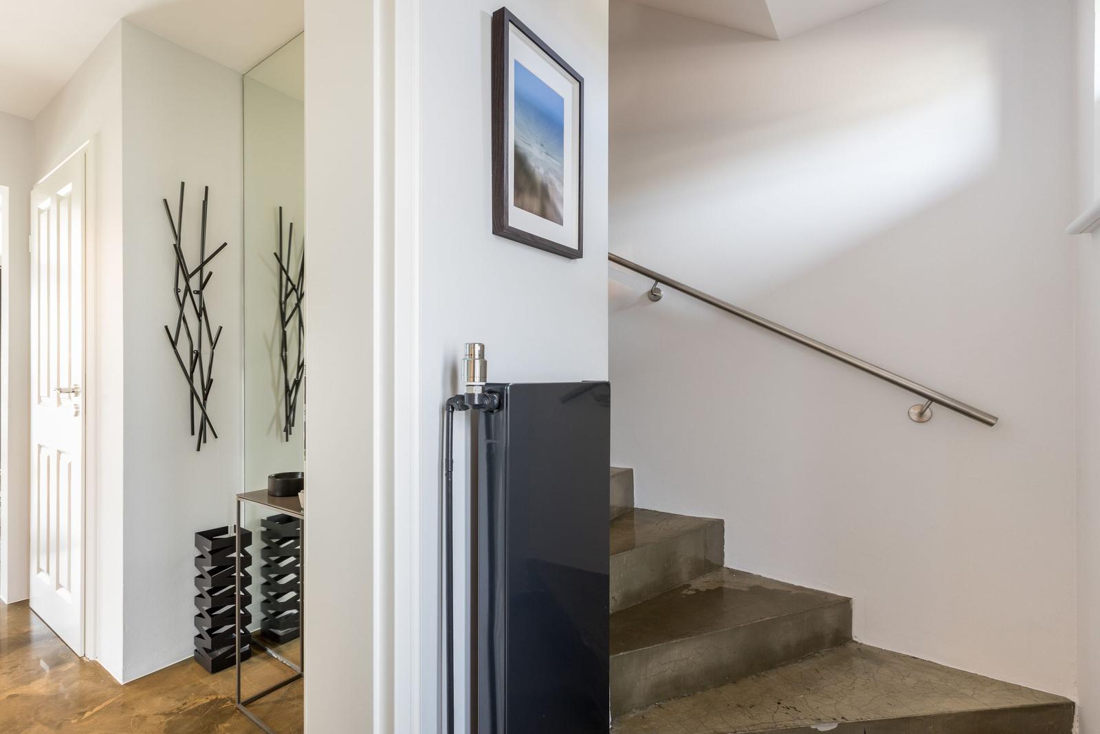 Haus mit Treppe, Spiegel und modernem Kunstwerk an der Wand.