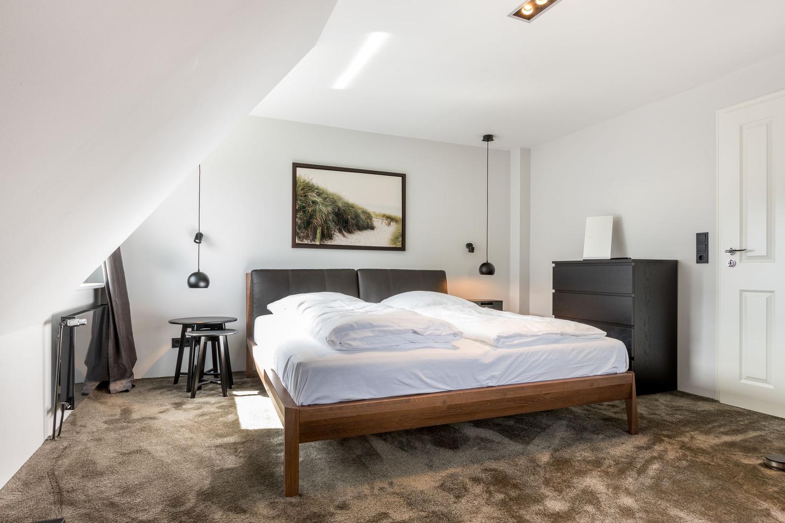 Schlafzimmer mit Doppelbett, Kleiderschrank und Wandbild.