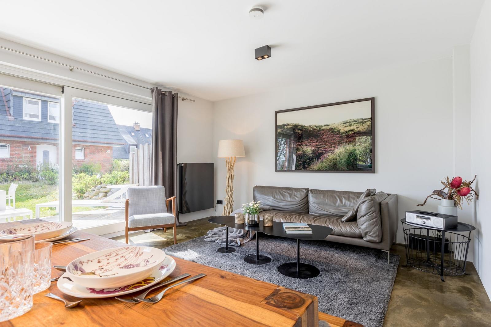 Wohn- und Essbereich mit Sofa, Tisch und Blick auf Garten.