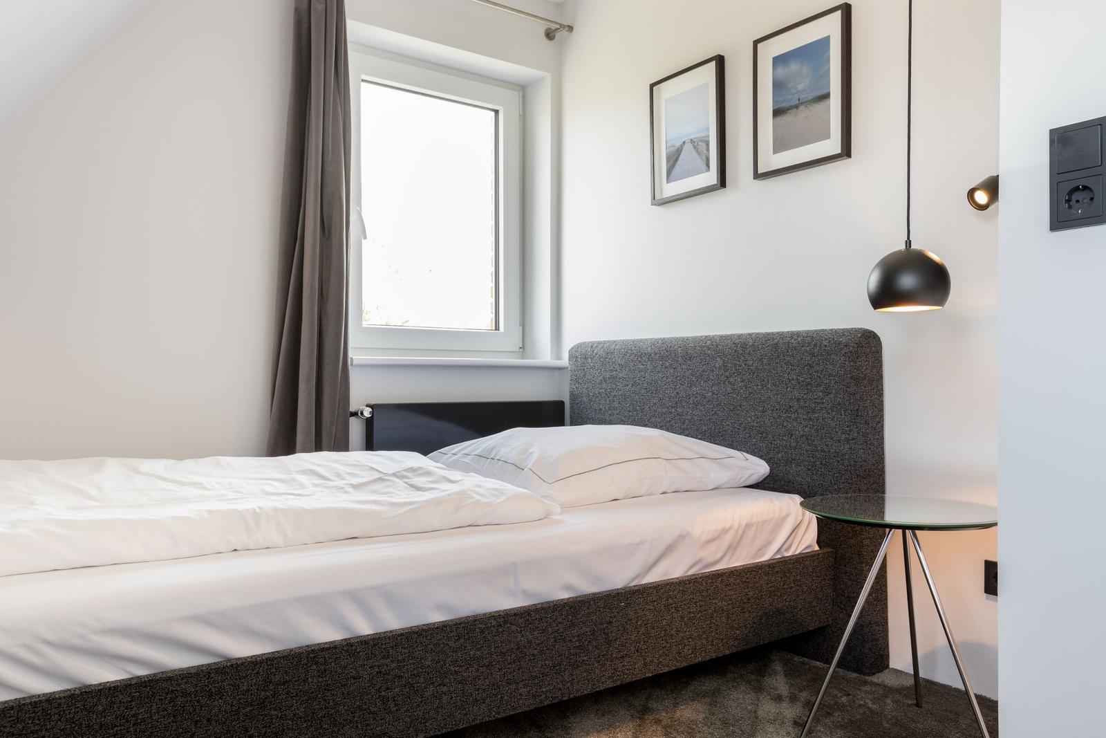 Schlafzimmer mit Bett, Fenster, Bildern und Tisch