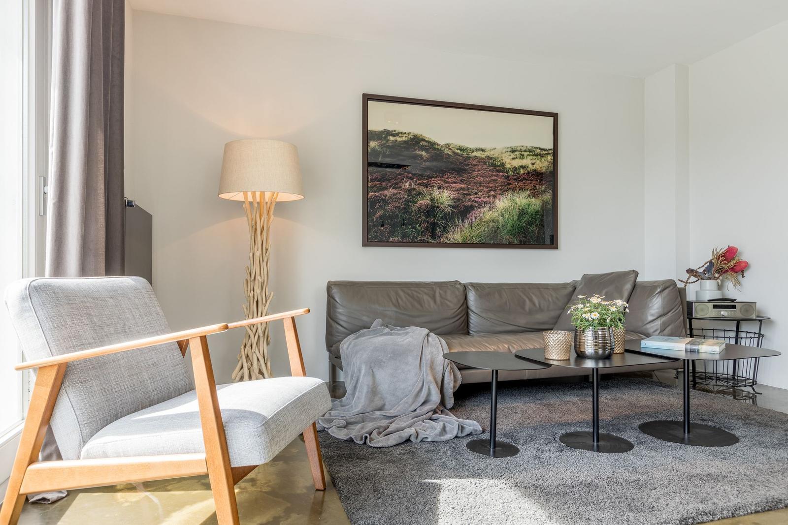 Ein Wohnzimmer mit grauem Sofa, Holzstuhl und Wandbild.