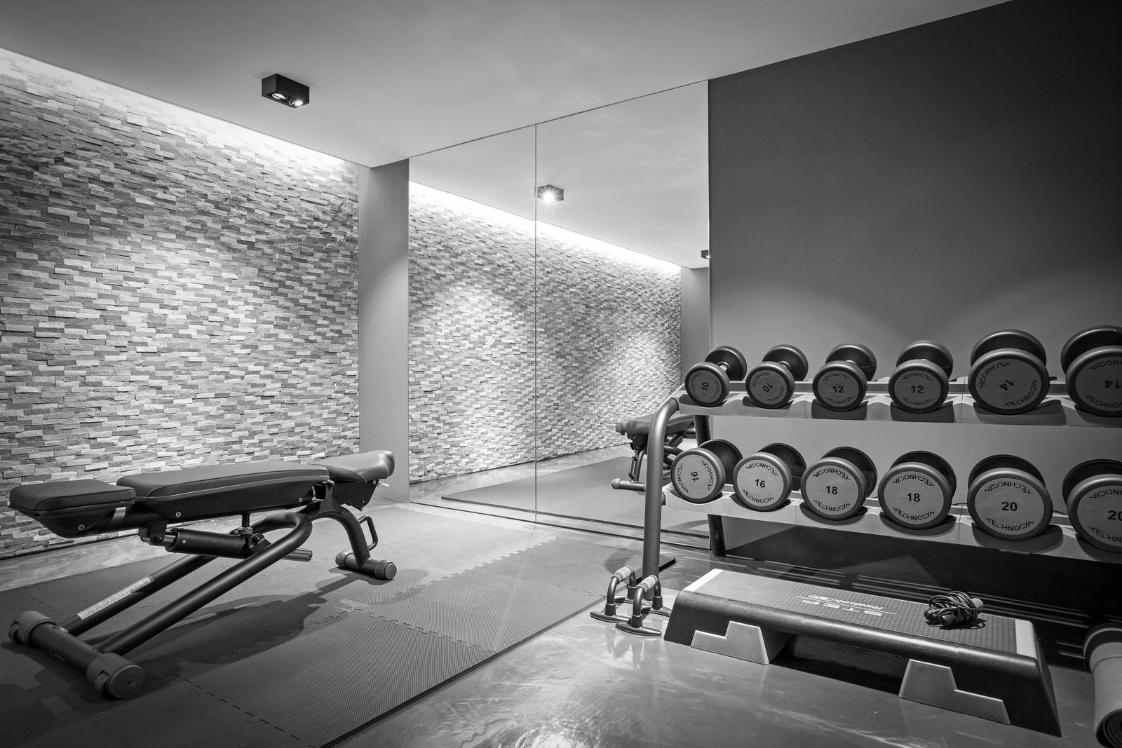 Fitnessraum mit Hanteln, Bank und Spiegelwand.