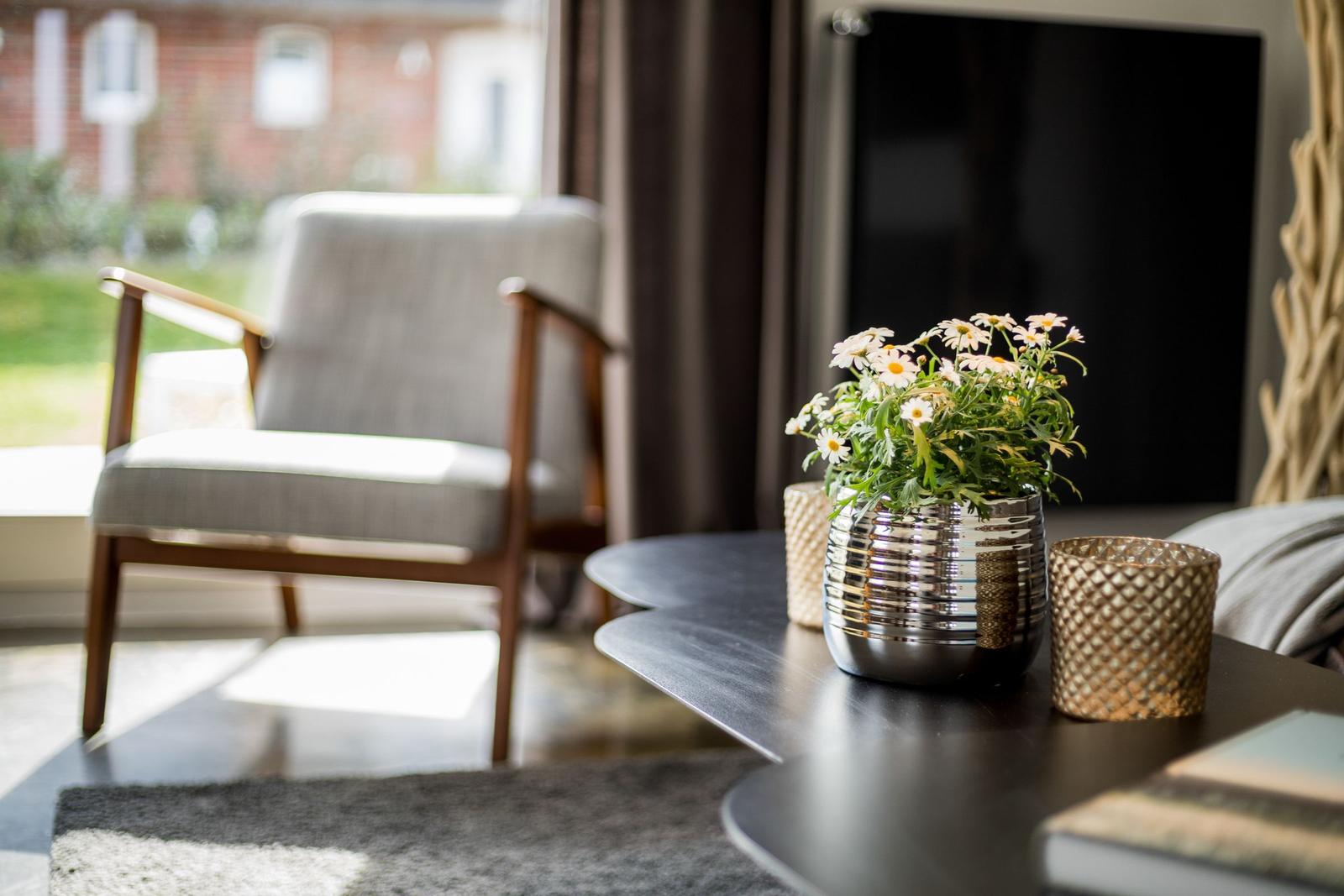Ein Wohnzimmer mit Sitzgelegenheit, Tisch und Blumenarrangement.