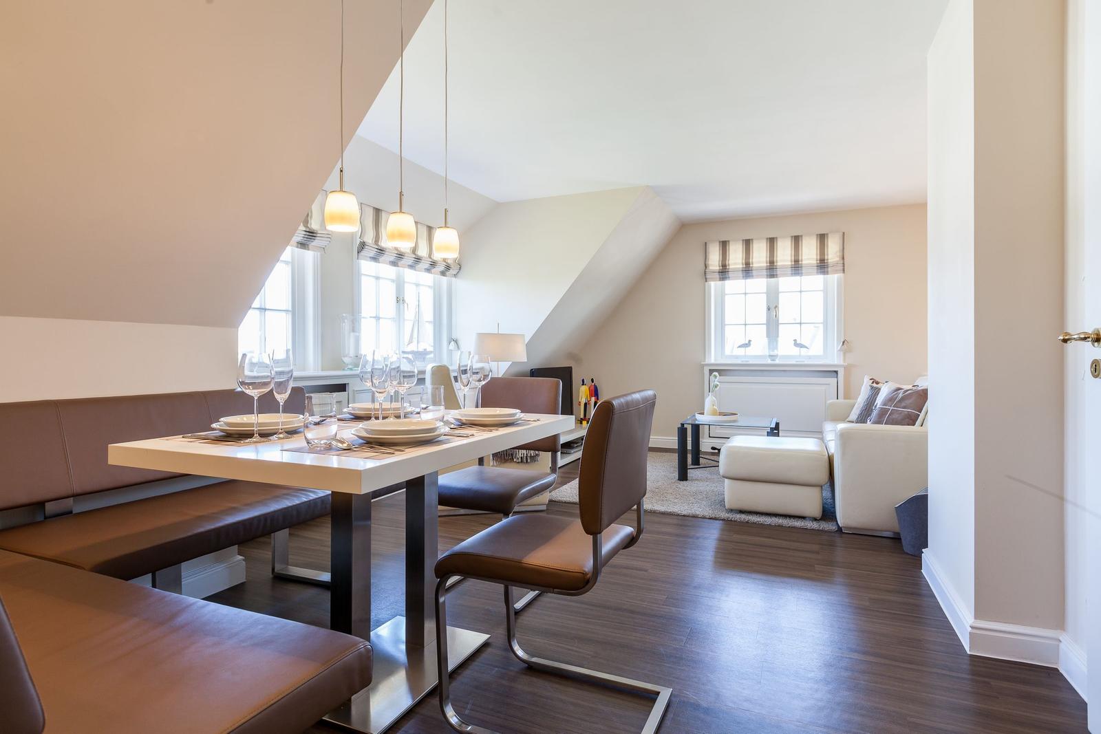 Dining area with table and chairs. Living room with sofa and windows.