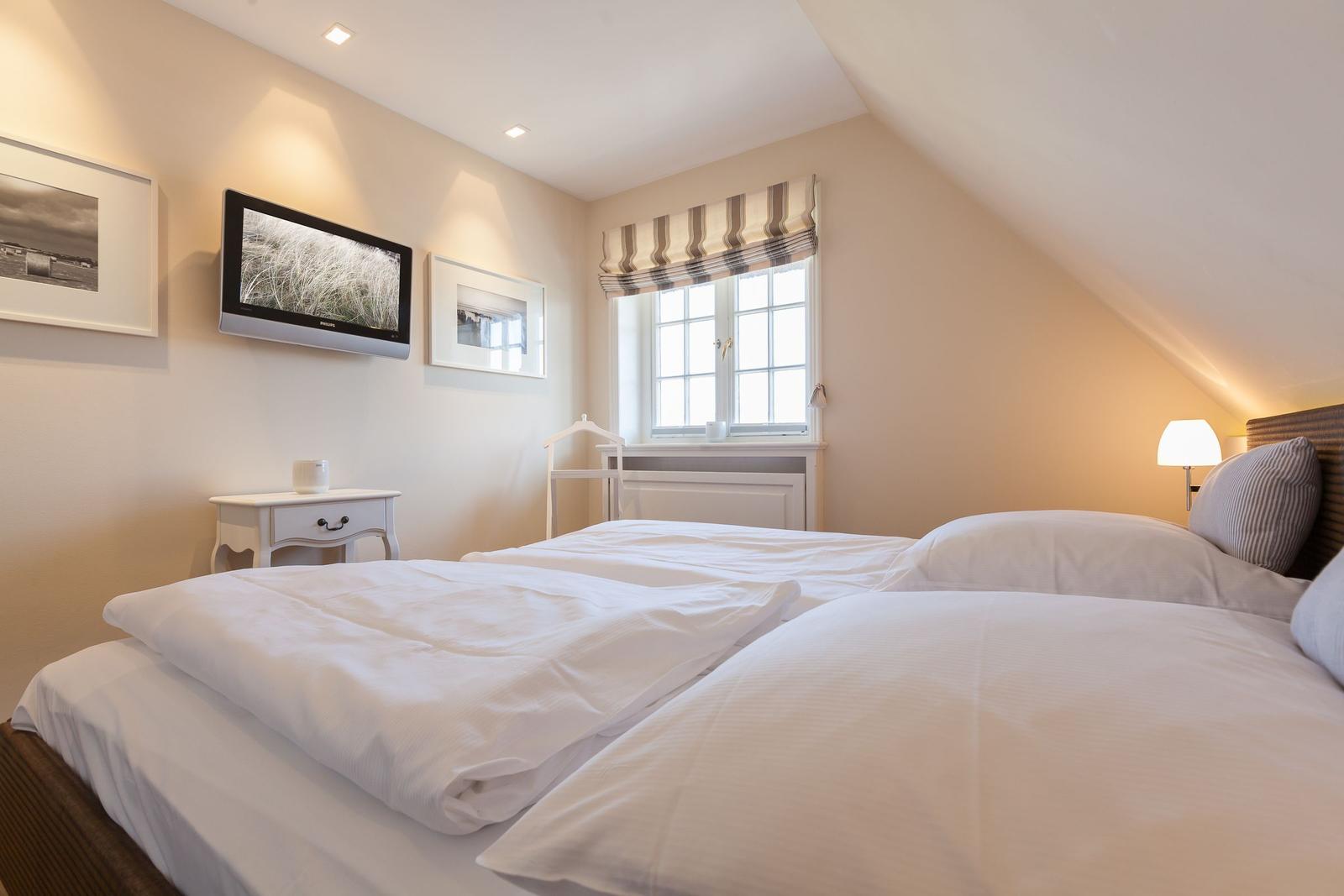 Bedroom with double bed, window, TV, and nightstand.