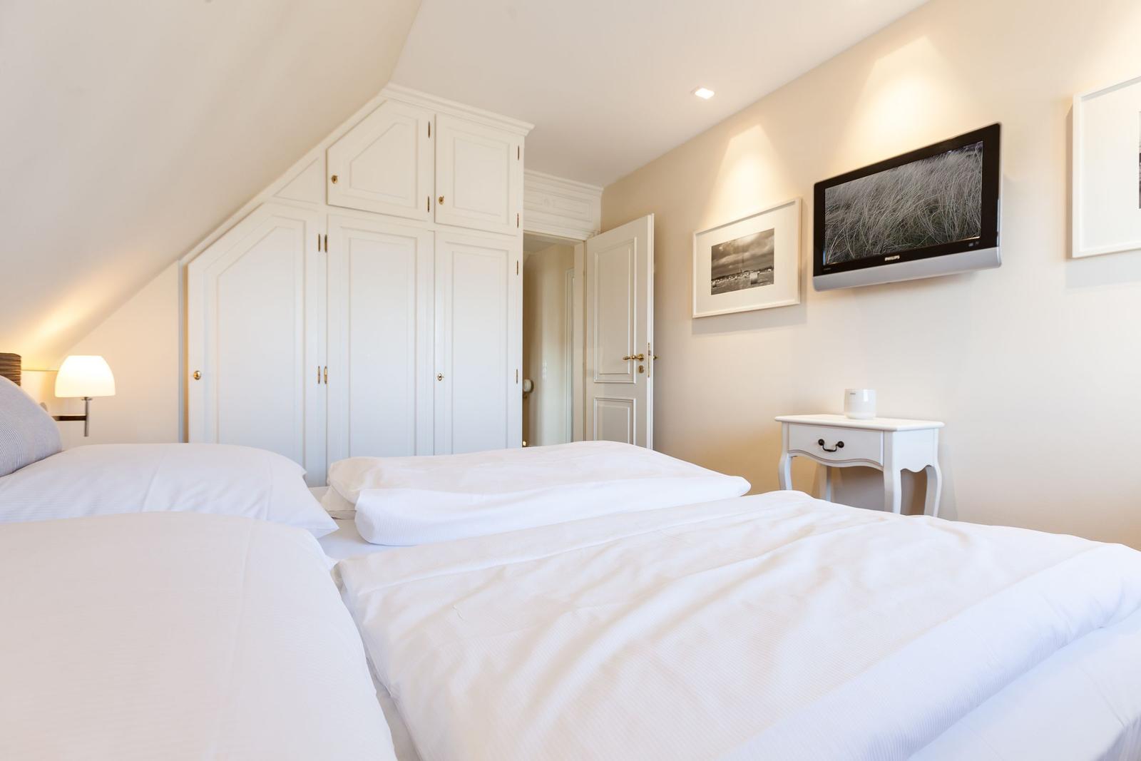 Room with double bed, white wardrobes, and wall-mounted TV.